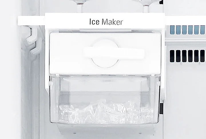 냉장고 내부의 얼음 제조기가 보입니다. 얼음 제조기에는 Ice Maker라는 텍스트가 적혀 있으며, 투명한 용기 안에 얼음이 담겨 있습니다. 주변은 흰색의 깔끔한 디자인으로 되어 있습니다.