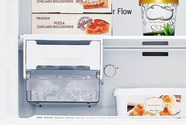 냉장고 내부 이미지로, 피자와 아이스크림 상자가 보입니다. 피자 상자에는 PEACOCK PIZZA CHICAGO BOLOGNESE라는 문구가 있으며, 아이스크림 용기에는 Our Story Begins라는 문구가 있습니다. 얼음이 담긴 투명한 서랍이 있으며, 서랍 위에는 조절 다이얼이 보입니다. 또 다른 용기에는 Mini Cream Puffs Classic Style이라는 문구가 있습니다.