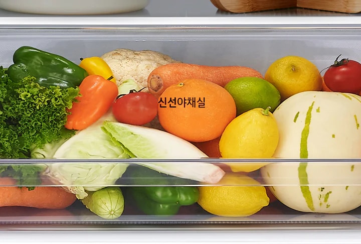 신선야채실 안에 다양한 채소와 과일이 가득 담겨 있습니다. 상추, 피망, 당근, 오렌지, 레몬, 라임, 토마토, 배추, 멜론 등이 보입니다.